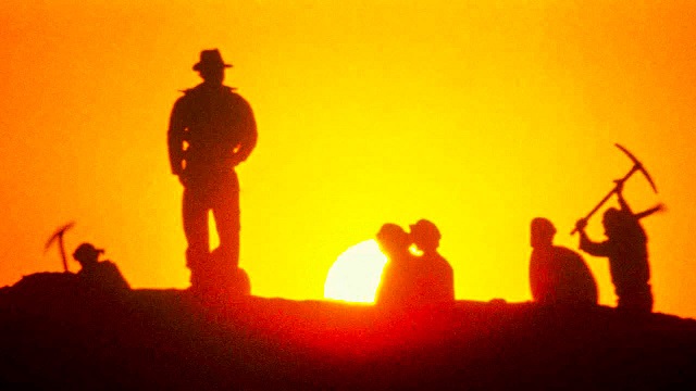 Men digging in the desert under a hot sun